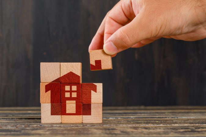stay at home concept on wooden table side view hand holding wooden cube scaled 1